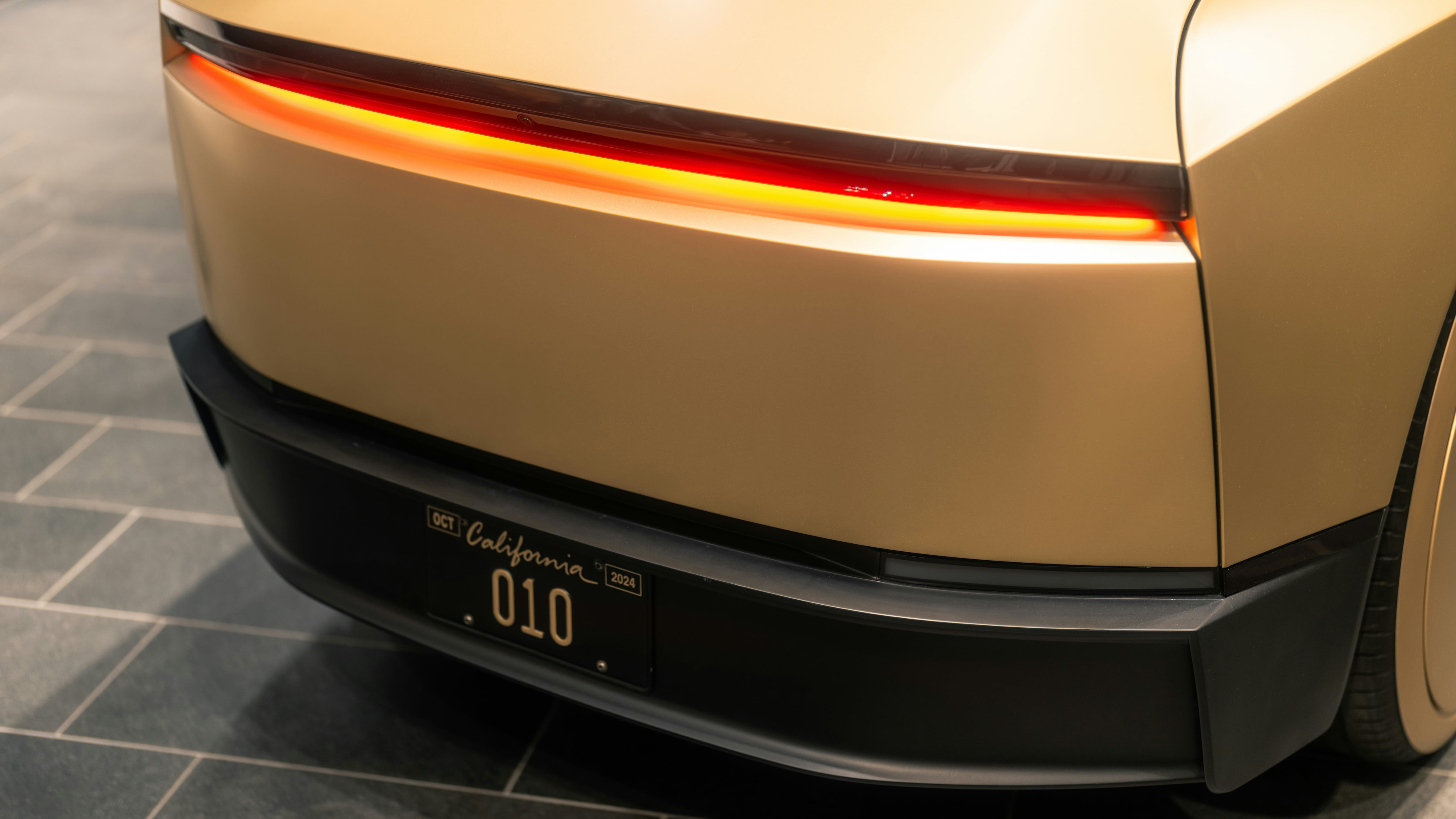 A gold Tesla with a California license plate on a tile floor