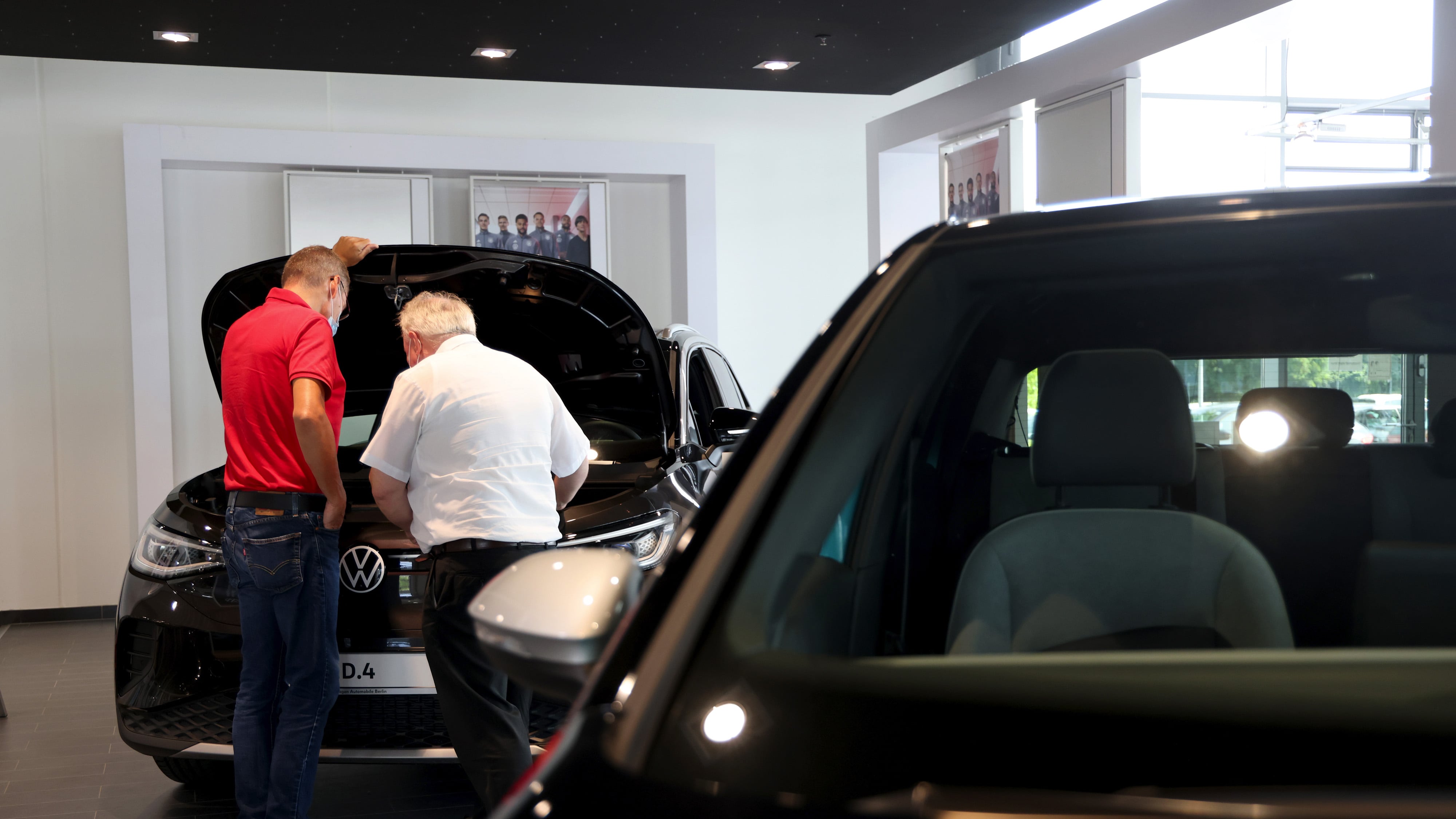 Customers look under the hood of a full-electric VW ID4 at a showroom in Berlin, Germany.